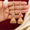 Premium gold finish long chain jhumka earrings with sparkling CZ white stones, ruby pink stones, and traditional dome design for bridal and festive wear.
