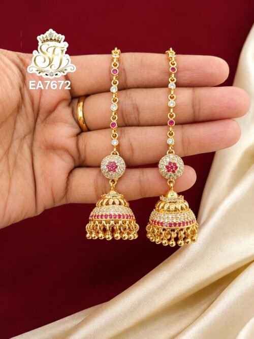 Premium gold finish long chain jhumka earrings with sparkling CZ white stones, ruby pink stones, and traditional dome design for bridal and festive wear.