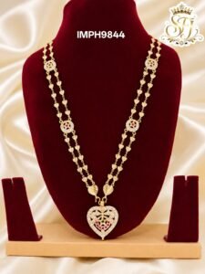 Premium gold finish heart pendant long haram with sparkling AD stones, ruby stone detailing, and heart link chain, perfect for bridal, wedding, and festive wear.