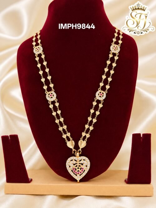 Premium gold finish heart pendant long haram with sparkling AD stones, ruby stone detailing, and heart link chain, perfect for bridal, wedding, and festive wear.