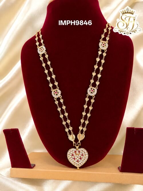 Premium gold finish heart pendant long haram with sparkling AD stones, ruby stone detailing, and heart link chain, perfect for bridal, wedding, and festive wear.