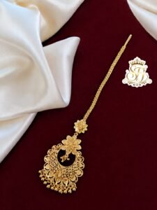 Round antique gold covering maang tikka with floral detailing.